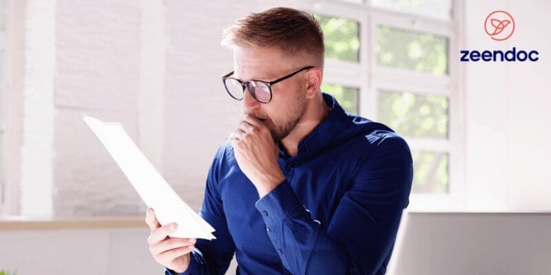 une personne assise à un bureau lisant une feuille